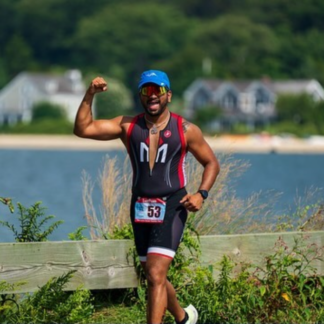 A man in a triathlon outfit is flexing his muscles.